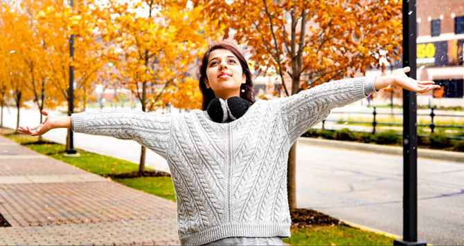 student smiling and holding arms out to the sky