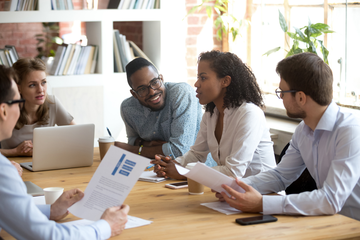 Team of business coworkers discussing and reviewing program documents at a table.