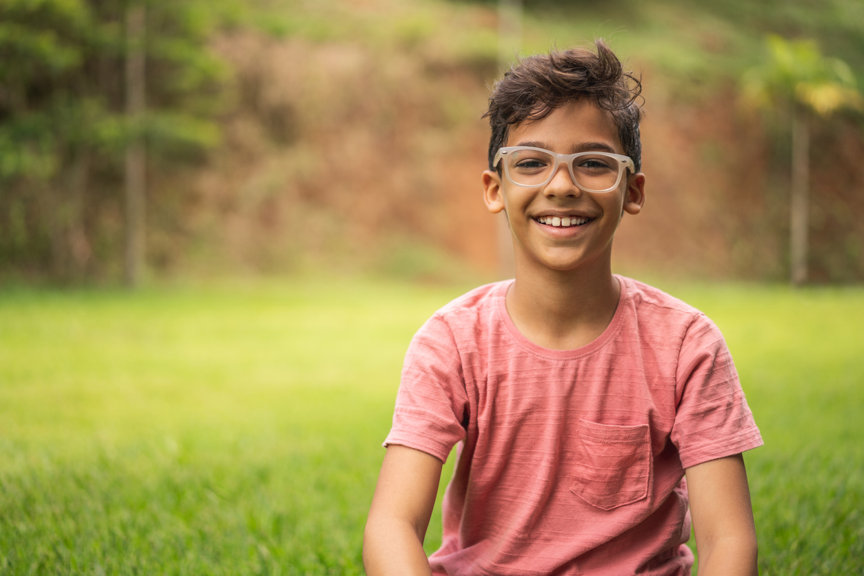 Portrait of little boy sitting on grass in private garden.