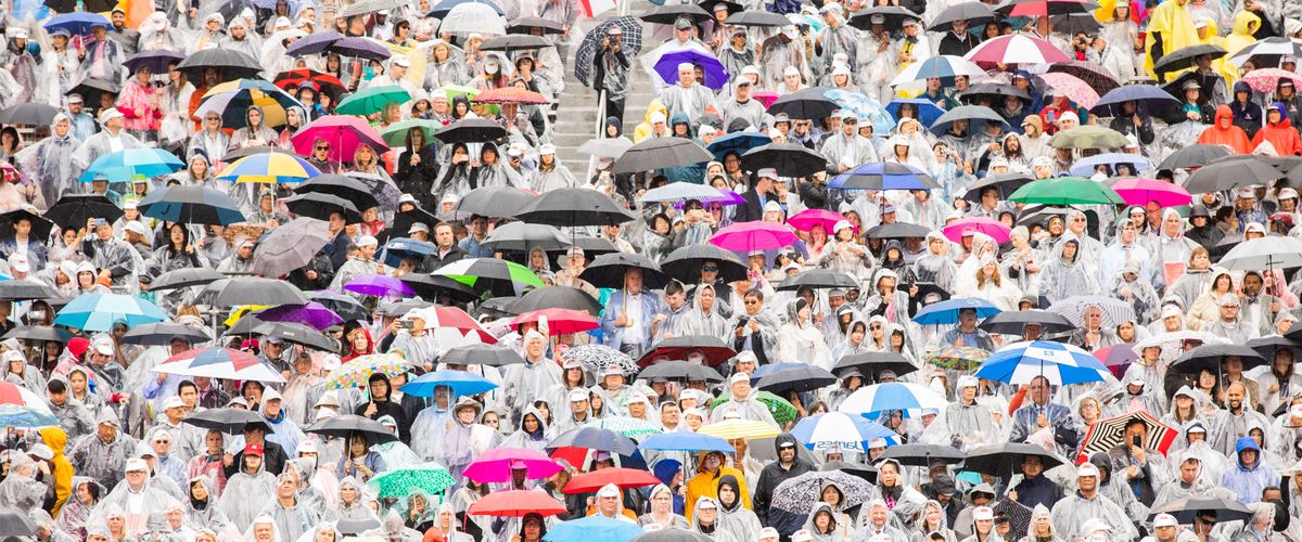 Families in the stands of Nickerson Field with ponchos and umbrellas to protect them from the rain at Commencement