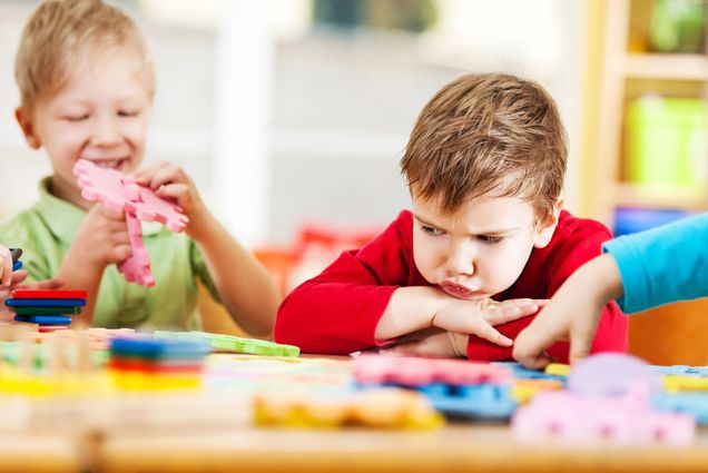 A photo of two children playing. One of them looks upset.