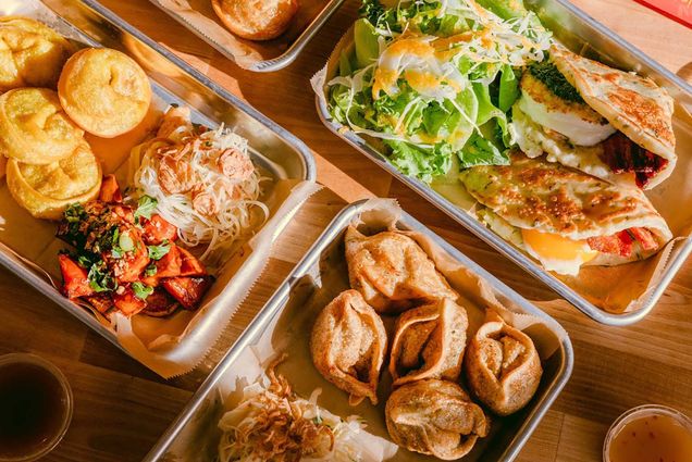 Photo: A flat-lay of the Mei Mei menu. Small, rectangular trays of dumplings, bao buns, and more are featured in an aesthetic layout, highlighted by the sun.