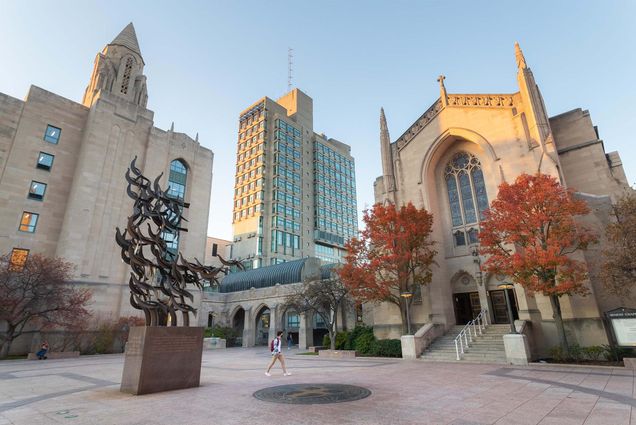 Photo: An empty plaza with a large ornate metal sculpture of flying birds in the center