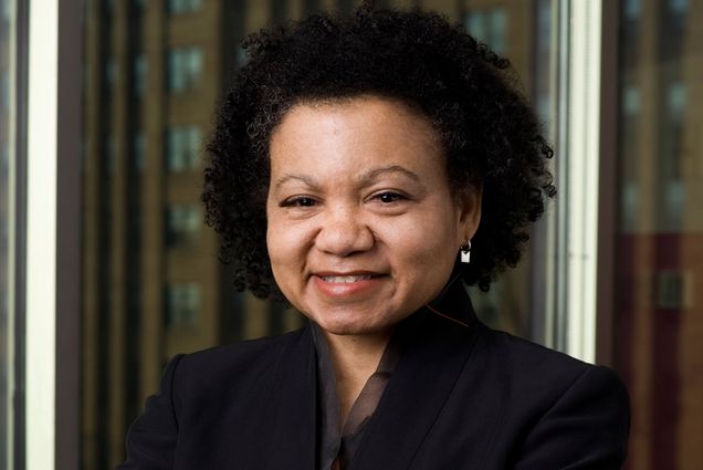 Photo: Headshot of a woman with dark hair wearing a black suit jacket and smiling