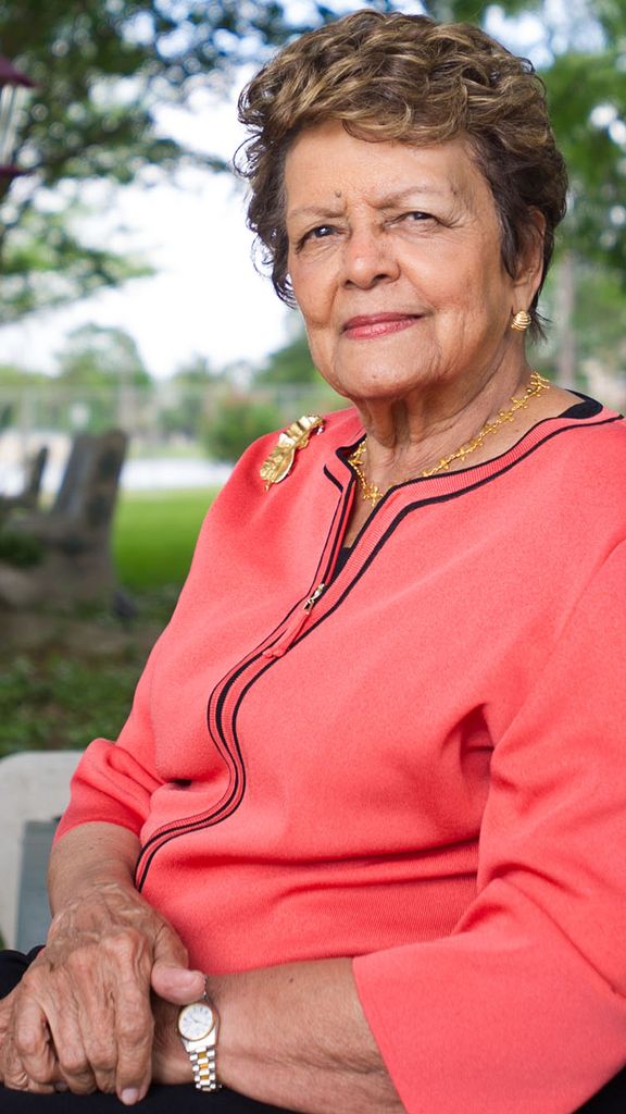 Photo: A picture of BU alum and civil rights advocate Sybil Haydel Morial wearing a long-sleeve peach top and sitting on a bench in a park