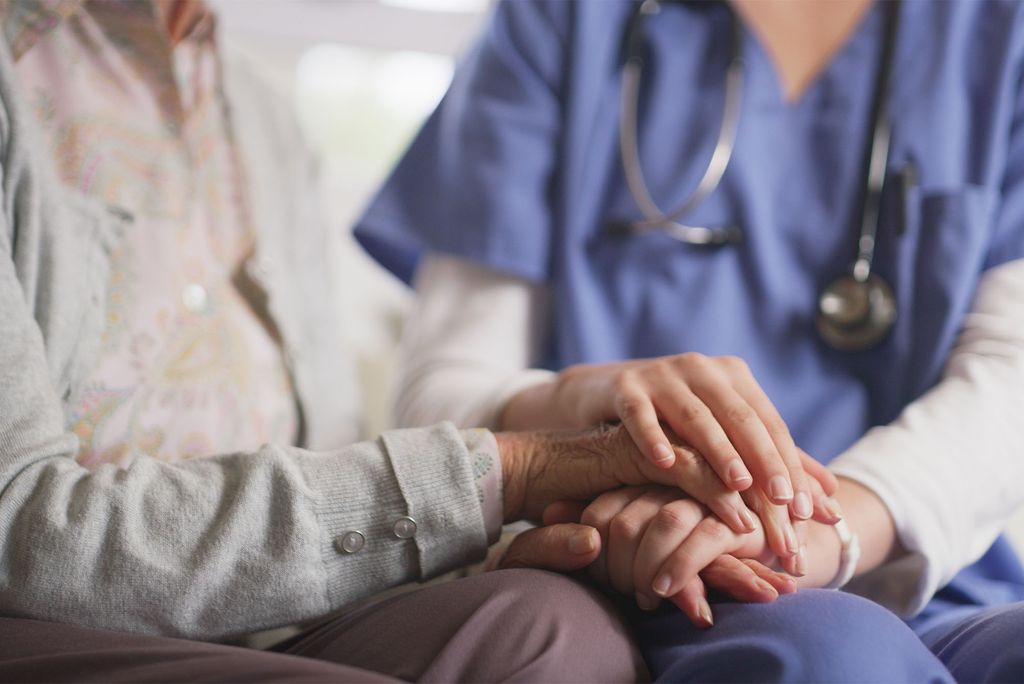 Photo: An elderly patient holds hands with a younger doctor