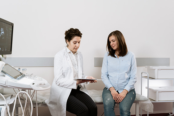 Health Law at BU Law. Doctor talking with woman at a hospital or medical center room.