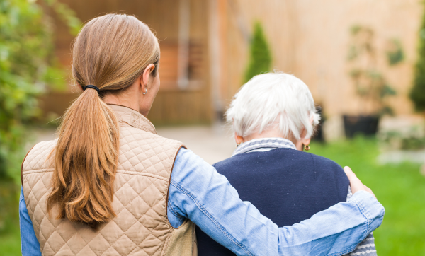 Young woman with her arm around an older individual with white hair