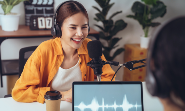 Young Asian woman use microphones wear headphones with laptop record podcast interview for radio