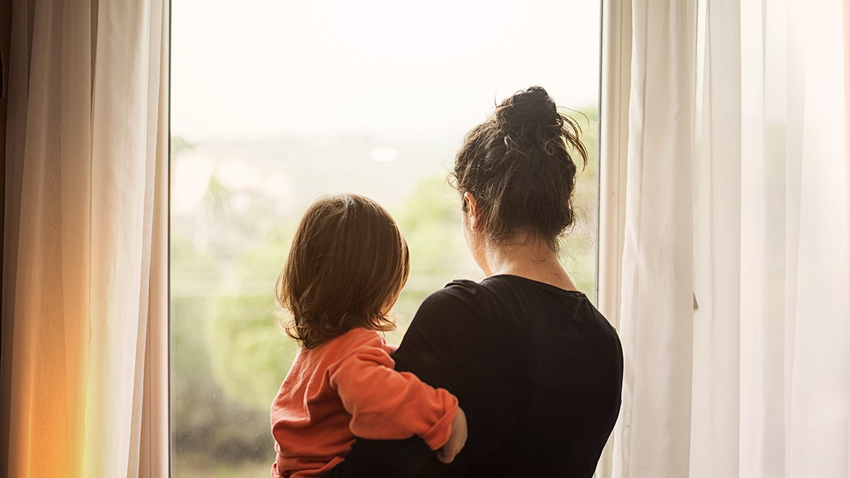 Mother carrying child and staring out the window.