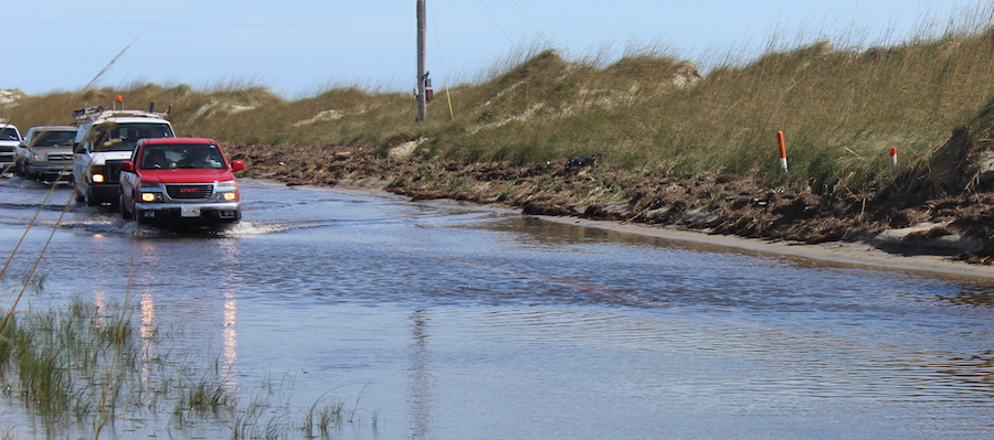 Cars on a coastal road plowing through water