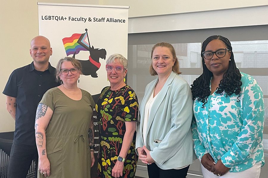 Attendees posing in front of LGBTQIA+ ERG banner