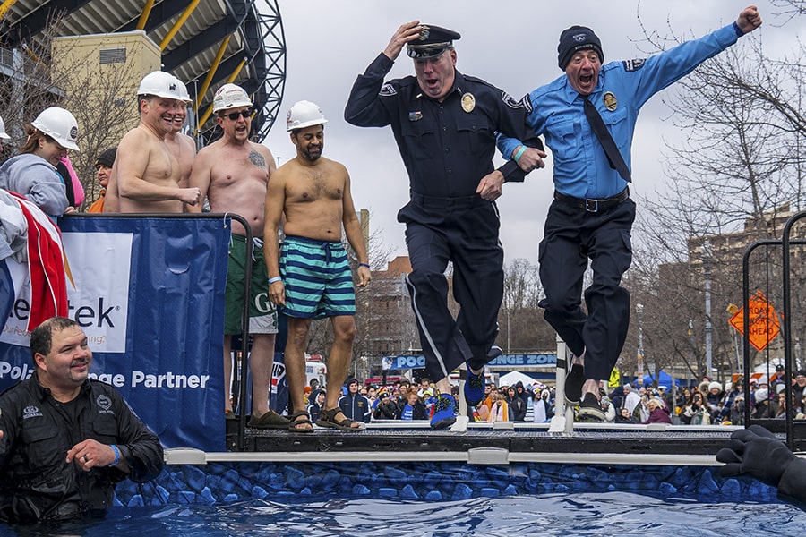 Two police officers jump into a pool