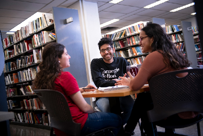 Three students sitting around a table in the library