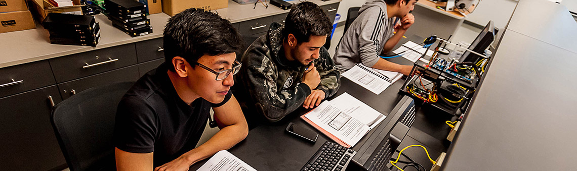 Three students looking at computer monitors