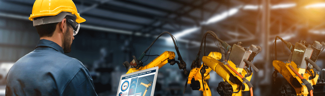 Electro-mechanical student wearing a yellow hard hat and looking at a screen