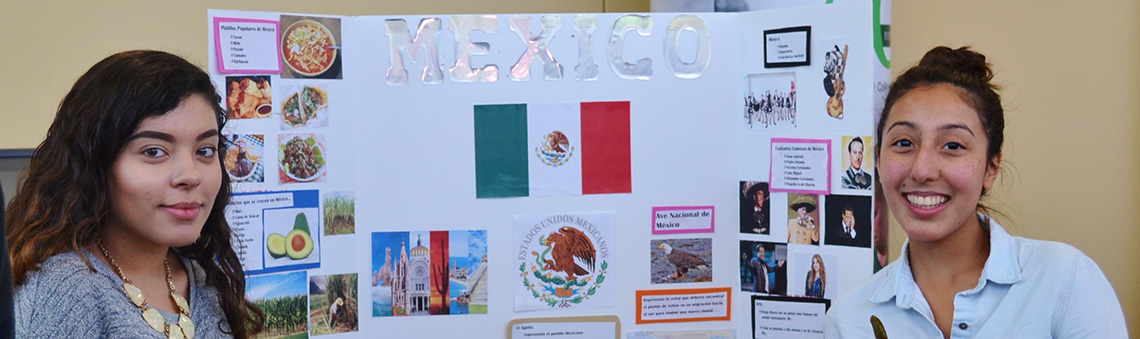 female hispanic students in front of a poster