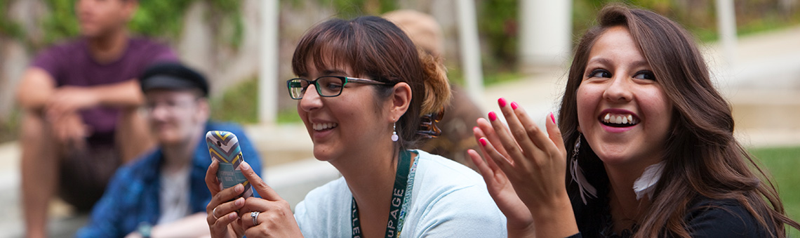 student looking at phone next to a student smiling