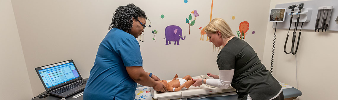 two women working on a mock baby in COD's mock clinic