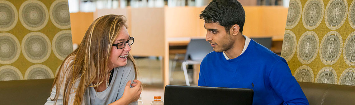 female and male students working on laptops