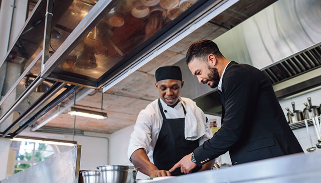 A man talking to a chef in the kitchen