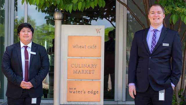 Inn at Water's Edge staff posing next to front door sign