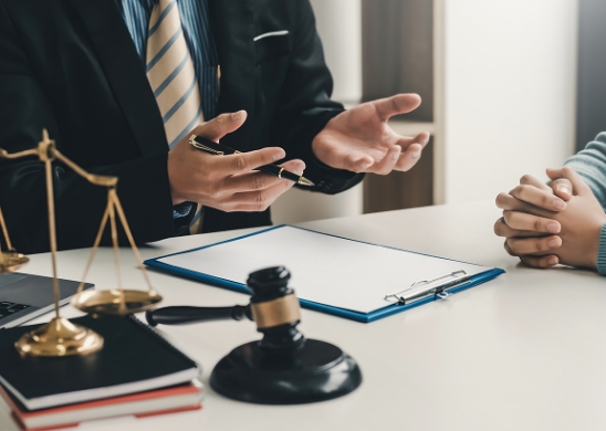 Close-up of a professional explaining legal papers to a client at a desk.