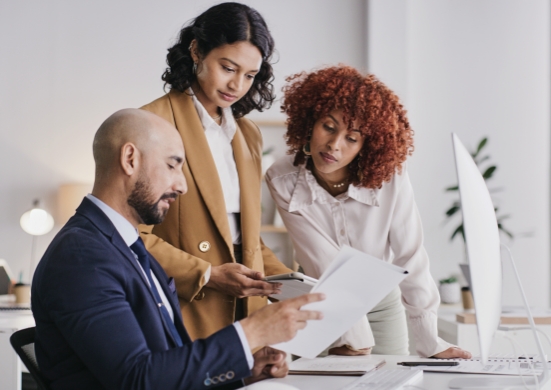 Small business team working on documents in front of computer.