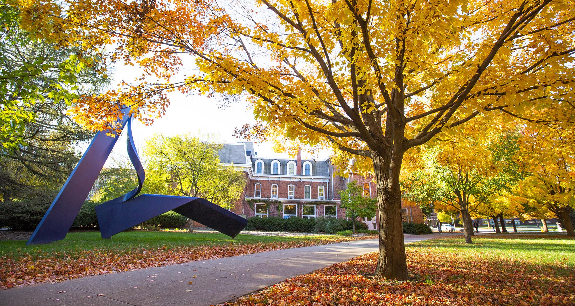 Autumn view of the Lab of Mechanics Building with a sculpture in the foreground.