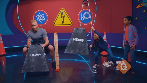 girl uses a pulley to lift a large weight in a competition about simple machines