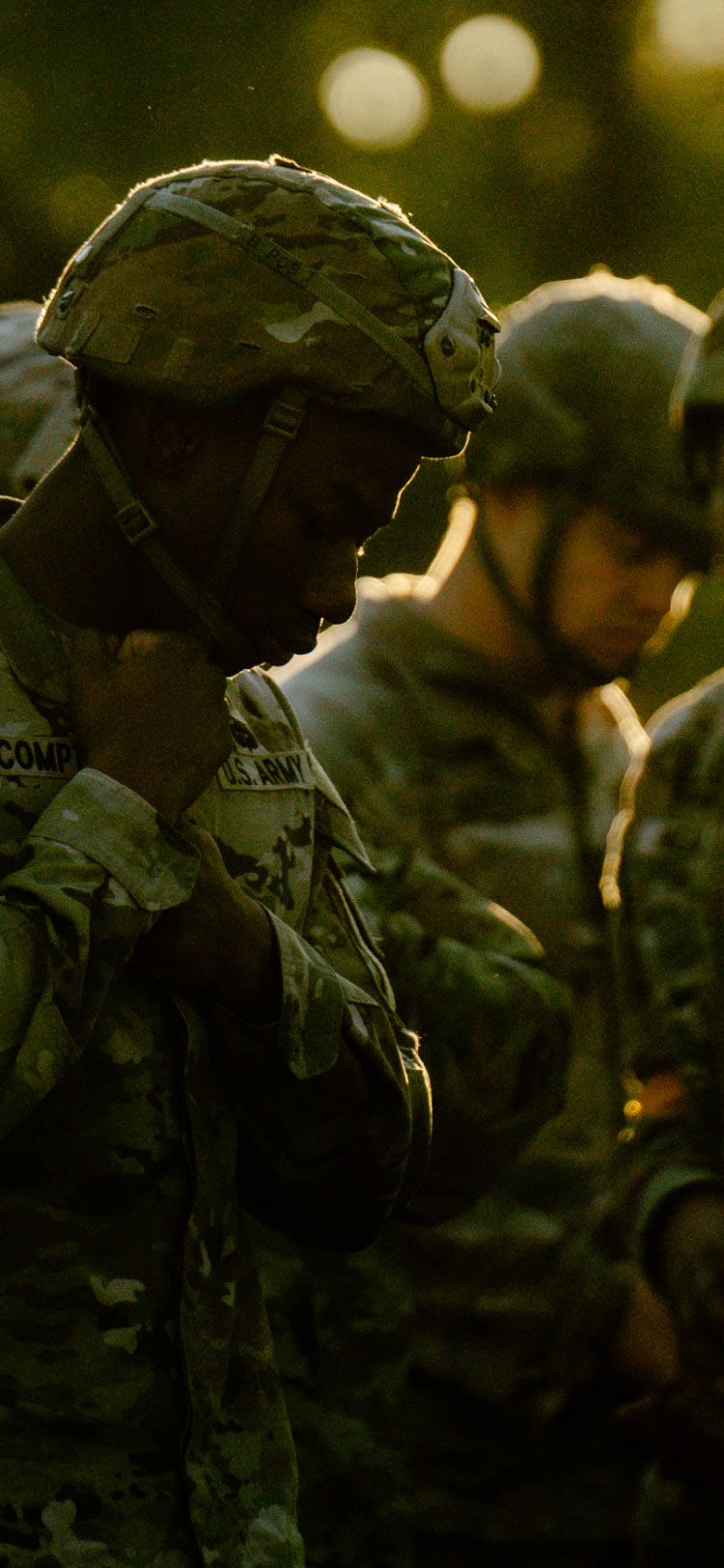 A male Soldier in combat uniform fastening the strap on his helmet