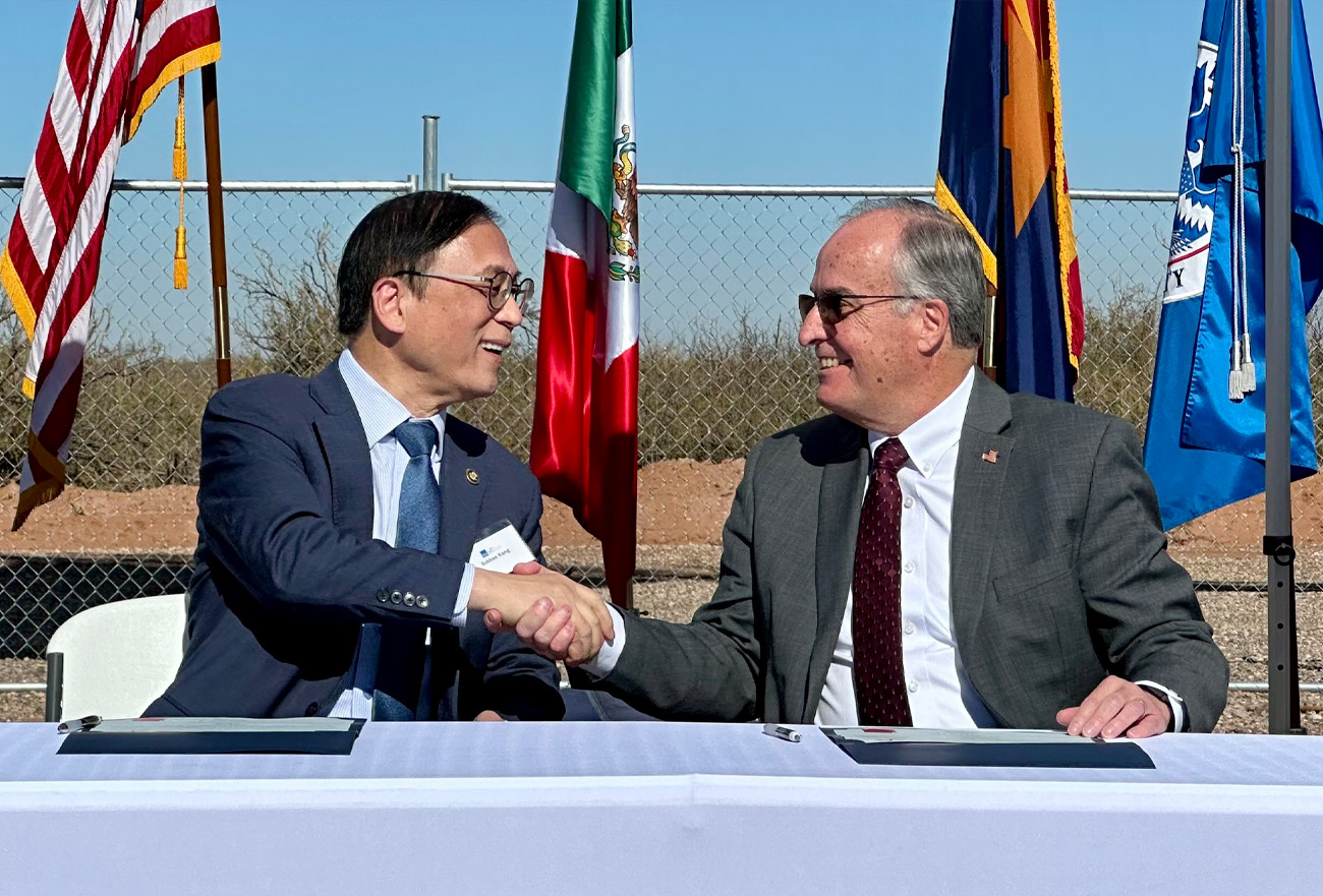 Two men shaking hands sitting at a table outside