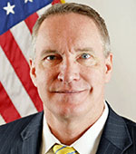 Headshot of Robert Carter. Robert has short light hair and is wearing a grey suit and yellow tie.