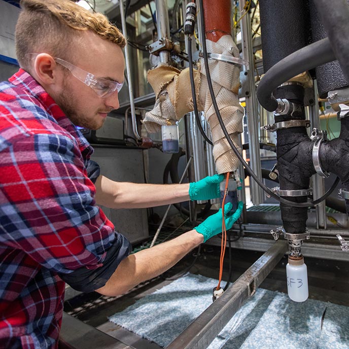 Mechanical engineering student works on pyrolizer equipment