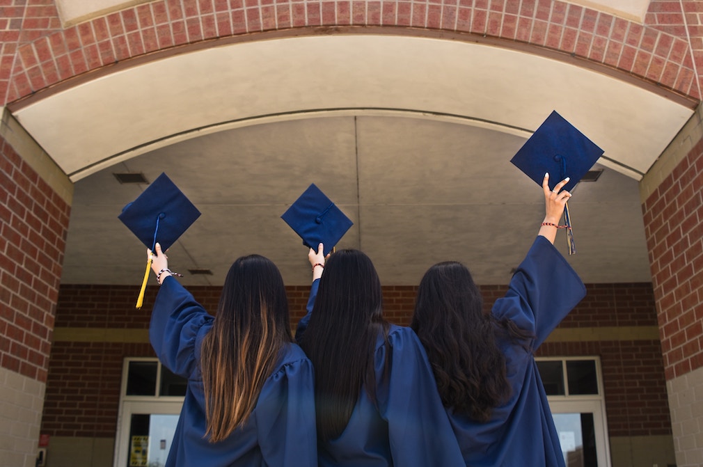 Three North Hennepin Community College graduates in graduation gowns