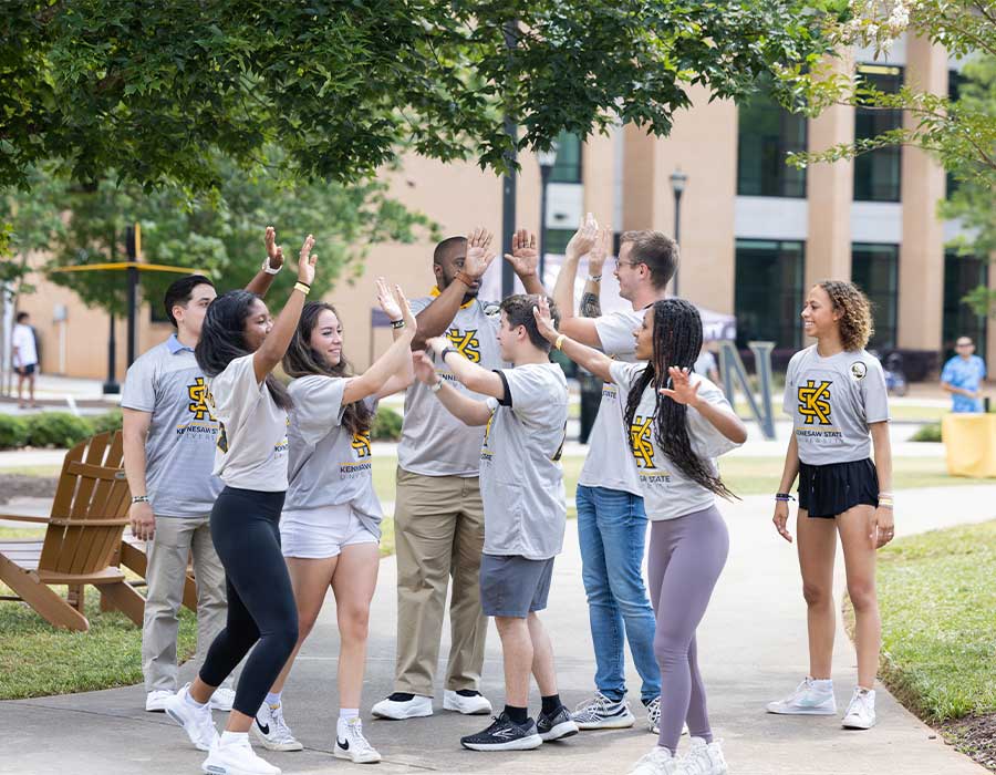 group of ksu first fight students high fiving each other outside.