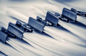 A close up of piles of documents joined together with bulldog clips