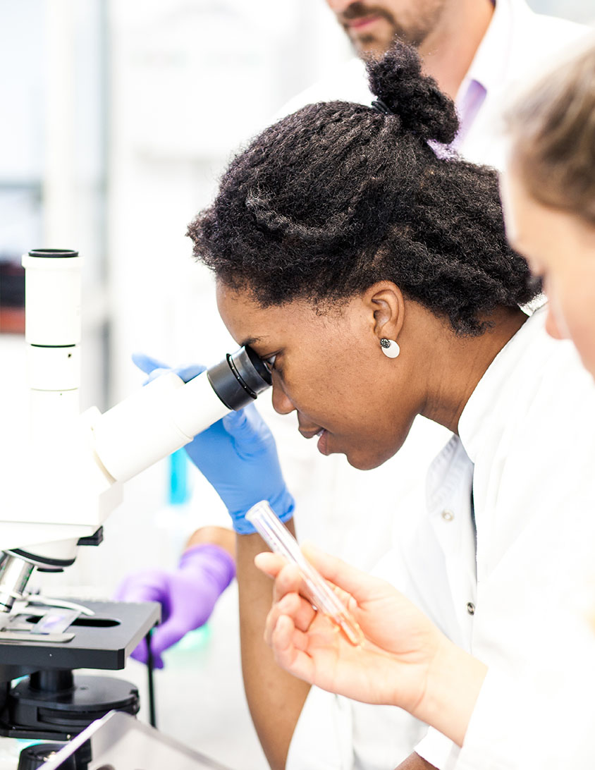 <p>A scientist looking into a microsope</p>