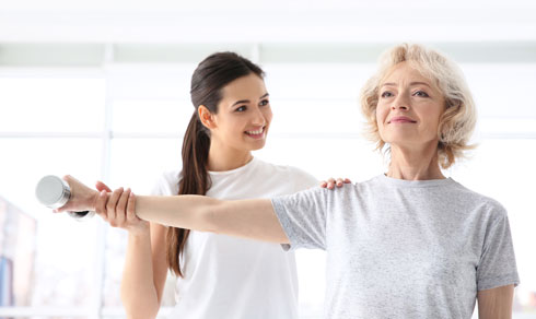 Woman using dumbbells with help of physical trainer.