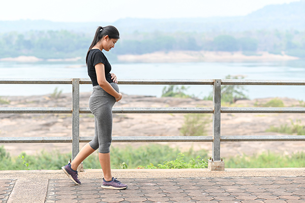 Pregnant woman walking while holding belly 