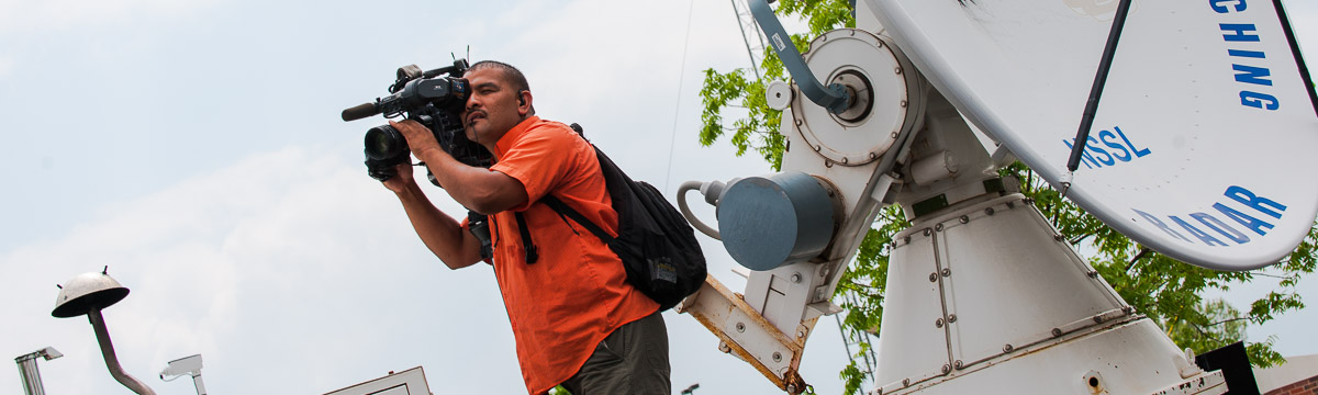 Media cameraman shooting from atop mobile radar truck