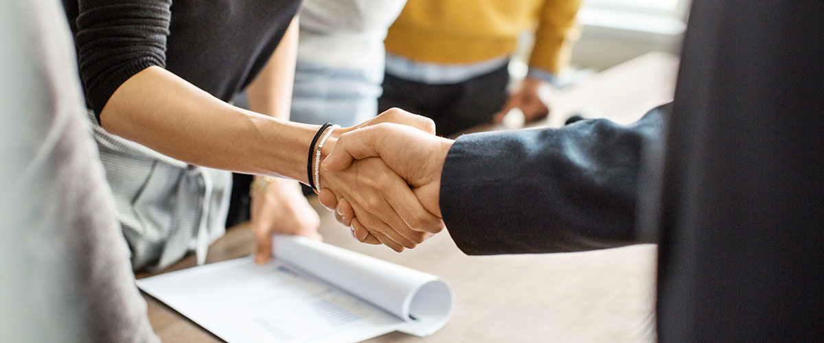 Close up of two people in black suits shaking hands 