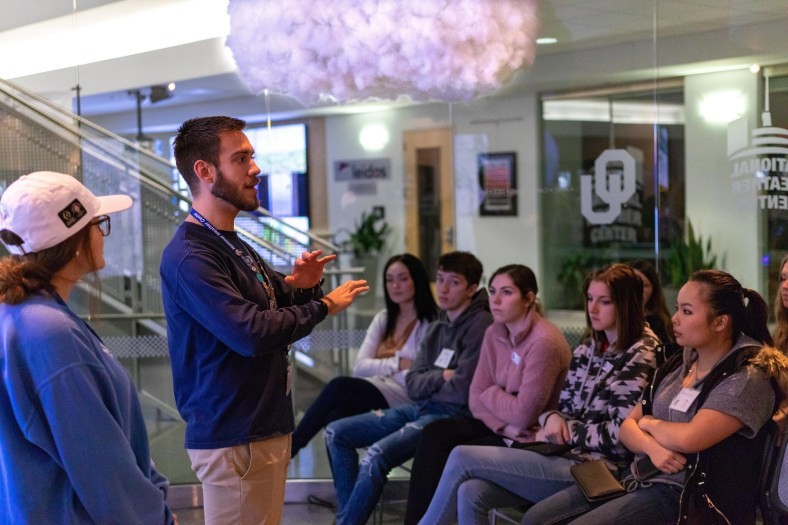 Two NWC Tour Guides give a presentation to a group of guests in the NWC Visitor Center. National Weather Center. OU.