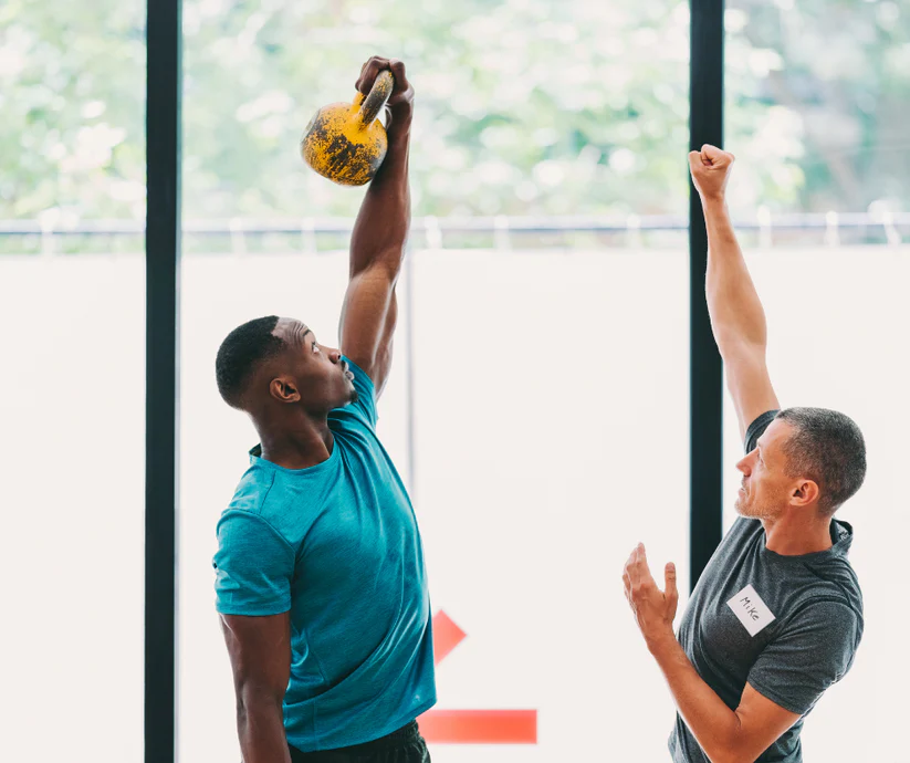 Personal trainer teaching a student to hold a kettle bell