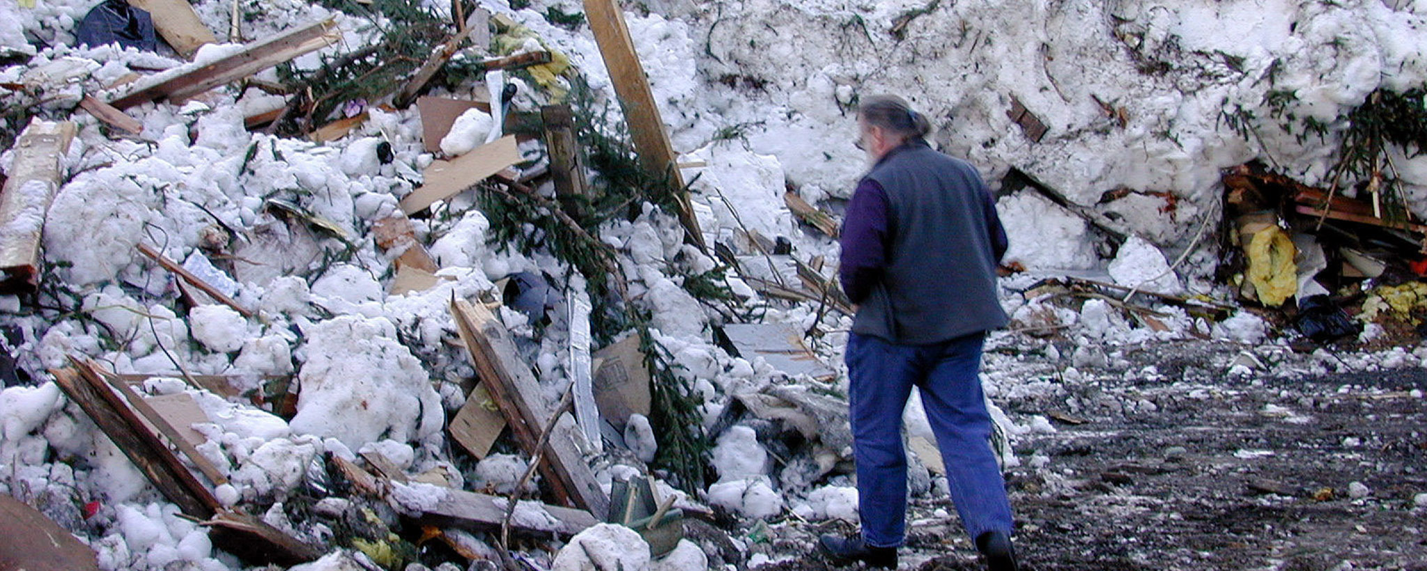 a man surveys damage after an avalanche