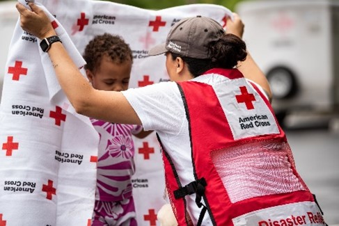 red cross volunteer covering child with blanket