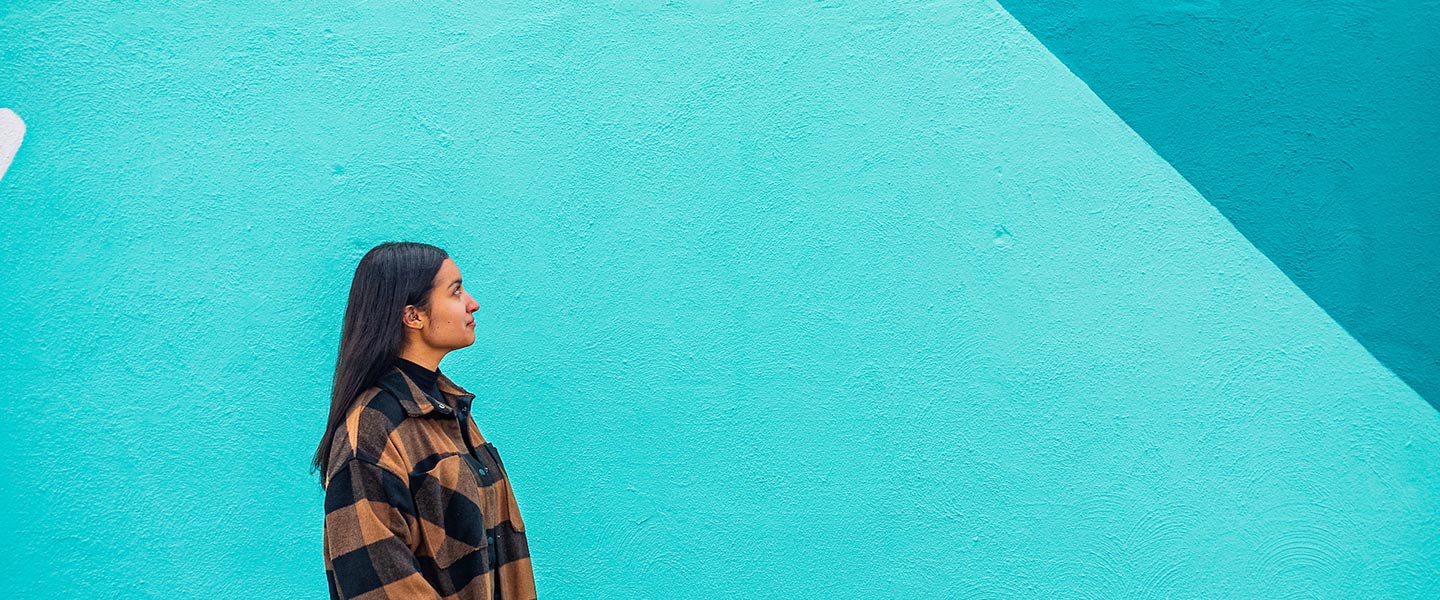 young woman stands in front of a colorful abstract mural