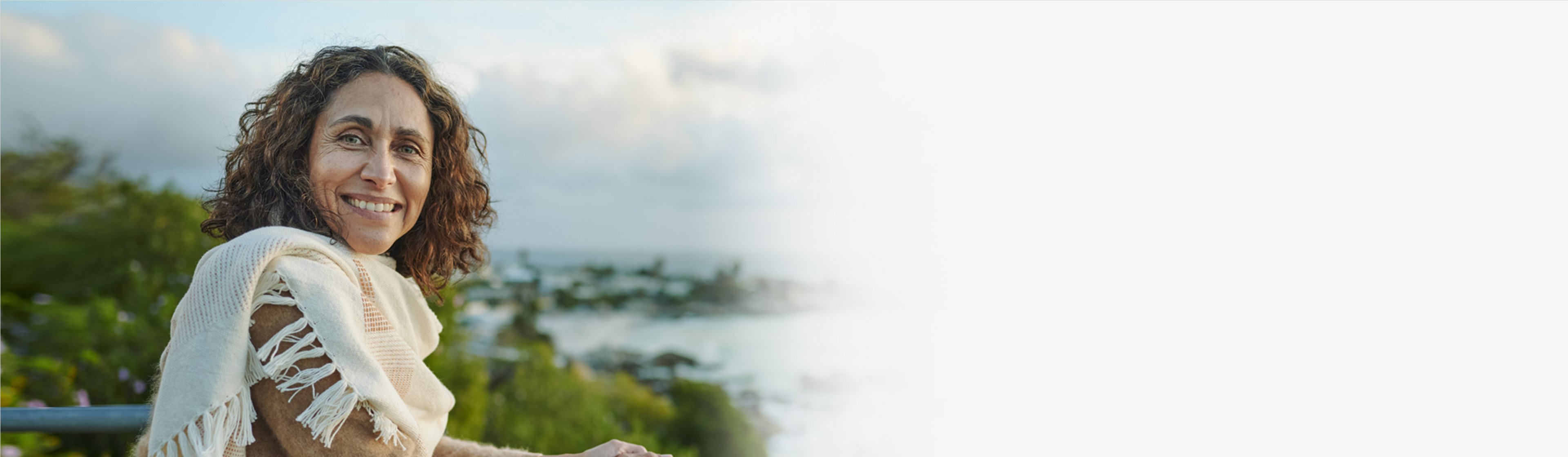 Woman standing on a pier overlooking a tree-lined coastline