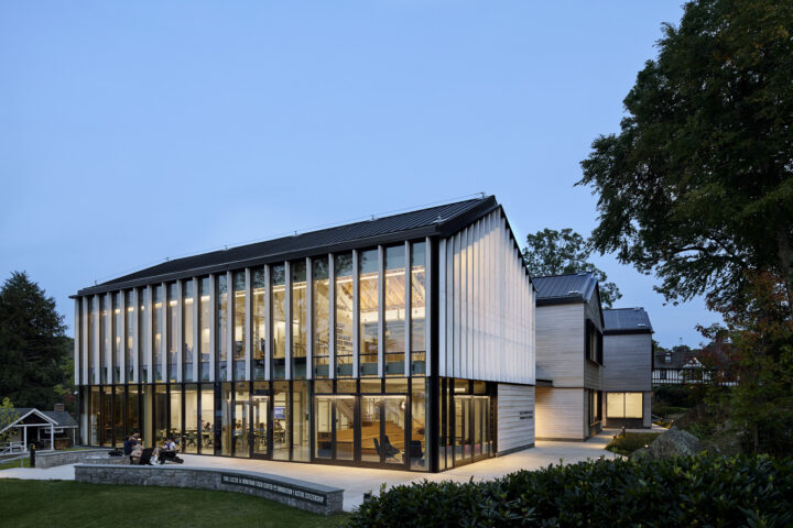 Night photo of building exterior with light streaming out from inside the glass facades between the wood fins