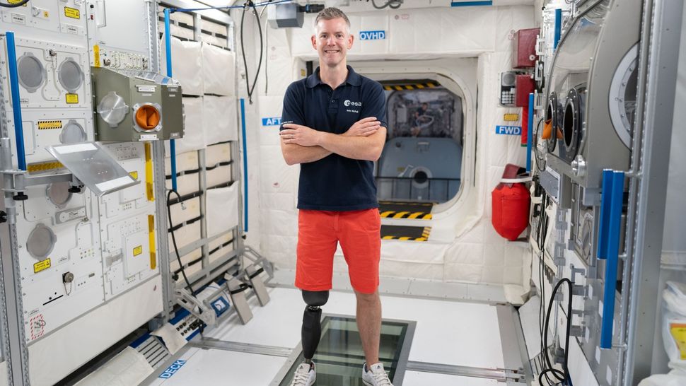 An astronaut with a prosthetic leg stands in a simulated ISS environment.